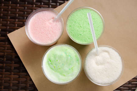 white, pink and green milkshakes in transparent cups with a straw.の写真素材