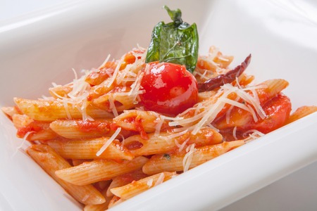 Pasta with spicy tomato sauce and basilicum sprinkled with Parmesan cheeseの写真素材