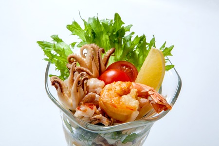Seafood cocktail - fried shrimp and octopus in a glass goblet decorated with lettuce and cherry tomatoesの写真素材