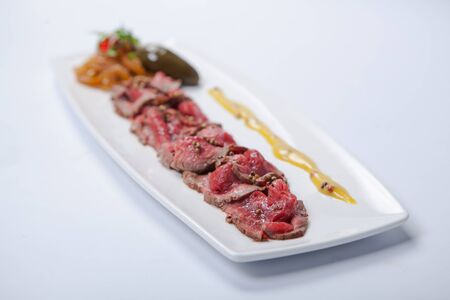 Beef carpaccio with sauce and vegetables on the white plate.の写真素材