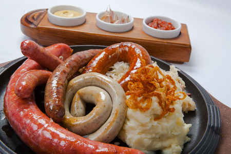 Assorted grilled sausages with mashed potatoes on a panの写真素材