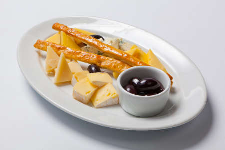 various types of cheese and olives on a white plateの写真素材