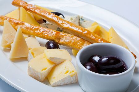 various types of cheese and olives on a white plateの写真素材