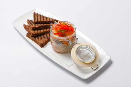 Black bread and herring in glass gar on a whtite plateの写真素材