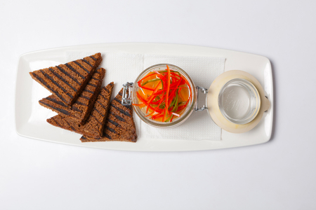 Black bread and herring in glass gar on a whtite plateの写真素材