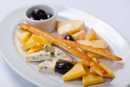 various types of cheese and olives on a white plateの写真素材