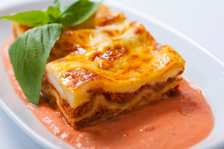 Lasagna on a white plate with leaf of herbの写真素材