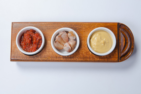 top view three sauces tomato, mayonnaise and garlic sauce in white bowl isolated on a wooden boardの写真素材
