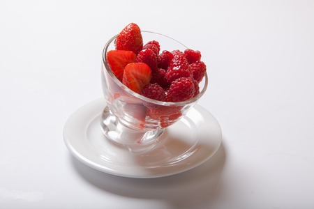 Fresh raspberry in a transparent glass plate. Ripe sweet raspberries in bowl on white table.の写真素材