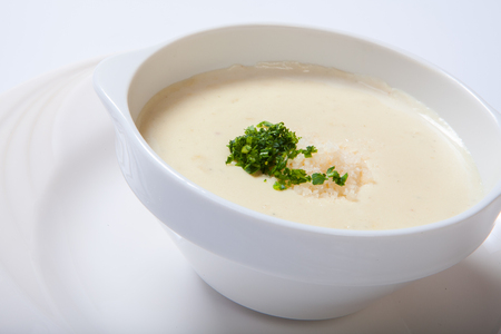 delicious creamy soup with parasley and cheese on white dish. Isolatedの写真素材
