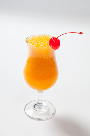 orange cocktail decorated with cherry on white background.の写真素材