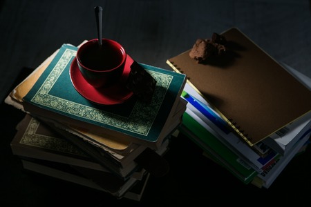 the coffee Cup and cookies and chocolate on stack of books.の写真素材