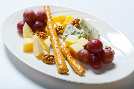 cheese and nuts, and grapes on the white plate.の写真素材