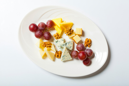 cheese and nuts, and grapes on the white plate.の写真素材