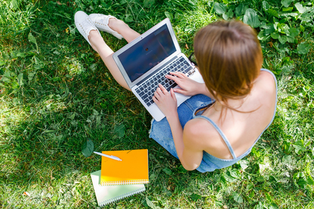Girl with laptop in the park sitting on a folding chairの写真素材