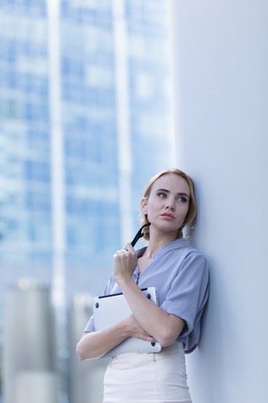 A beautiful woman standing in the center of the city holding a notebook in her handsの写真素材