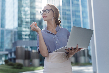A beautiful woman standing in the center of the city holding a notebook in her handsの写真素材