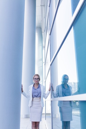 Stressed business woman standing next to the wall of an office buildingの写真素材