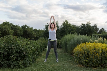 Young happy sporty girl stretching after jogging exercise in the city park