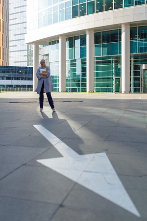 Loneliness business woman with cup of coffee and smartphone standing among the downtownの写真素材
