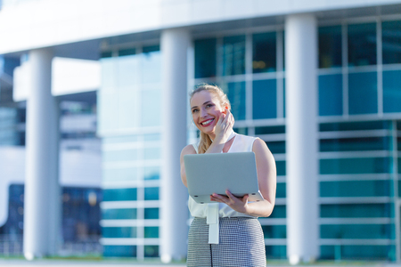 Successful business lady using a laptop in the middle of a business centerの写真素材