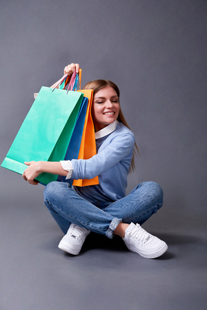 Portrait of beautiful happy girl with packages sitting on the floor.の写真素材