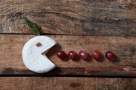 Soft gourmet cheese with grapes and rosemary on wooden tableの写真素材