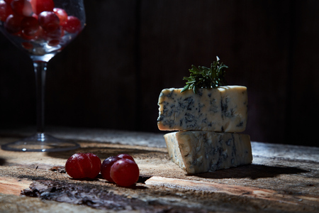 Layout of wineglass with grapes on wooden table with blue cheeseの写真素材