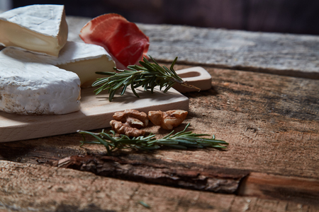 Delicious assorted appetizer with cheese and prosciutto and walnuts on wood tableの写真素材