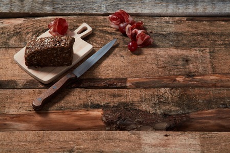 Top view of arranged corkscrew with slices of prosciutto and wholegrain bread on wood planksの写真素材