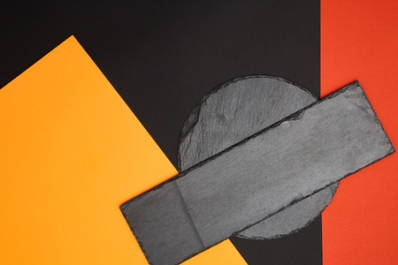 Composition of empty black slate serving board on multicolored background with geometric compositionの写真素材