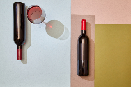 Layout of bottles and glass of red wine on colorful paper backgroundの写真素材