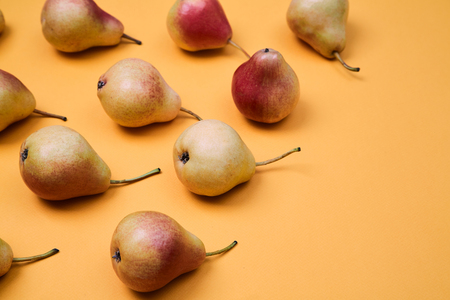 Ripe juicy pears placed on orange background. Colorful fruit pattern or background