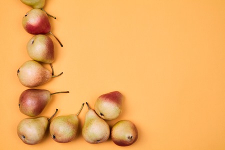 Ripe juicy pears placed on orange background. Colorful fruit pattern or background