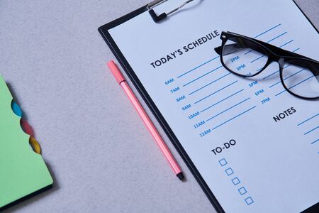 Time management deadline and schedule concept: schedule sheet, glasses and notebook on grey backgroundの写真素材