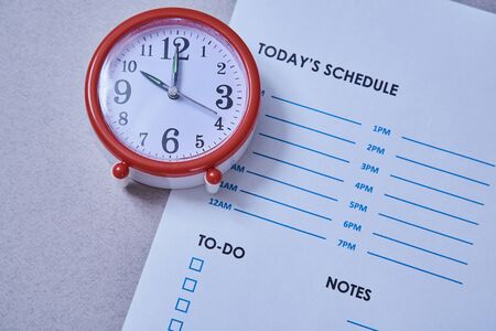 Time management deadline and schedule concept: alarm clock on the background of the scheduleの写真素材