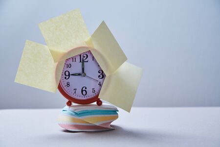 Time management deadline and schedule concept: clock with stickers on the stack of stickers.の写真素材