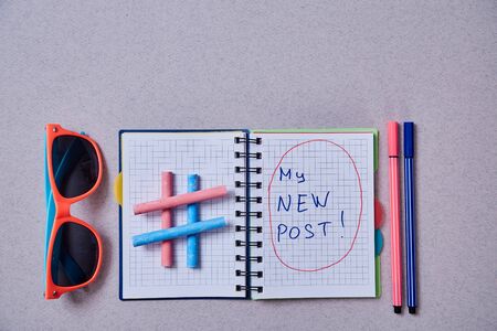 Blogging, blog and blogger or social media concept: notepad and hashtag symbol on grey background.
