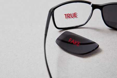 Fake news, disinformation or false information and propaganda concept. . Broken glasses with the inscriptionの写真素材