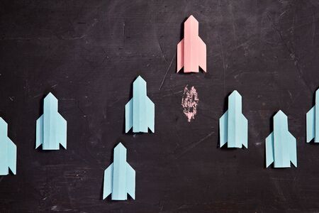 Think different and individuality vision or idea concept.Red paper rocket flies ahead of the group
