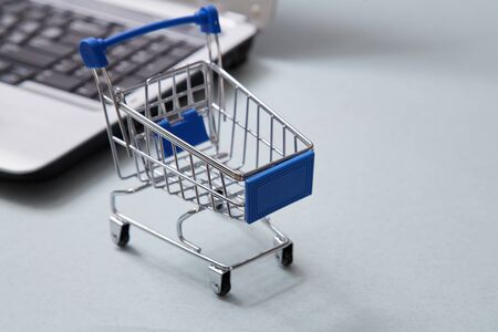 Internet e-commerce and shopping online. Basket next a laptop backgroundの写真素材