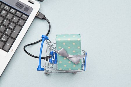Delivery, online shopping and business concept. Gift lying in the basket and laptopの写真素材