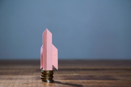 Business, finance, investment, saving and stock market concept. Paper rocket taking off from a stack...