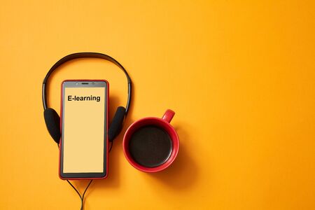 E-learning or online education concept. Webinar, internet lesson or courses. Headphones, coffee cup on yellow backgroundの写真素材