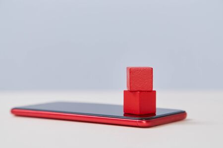 Red wooden cubes on modern smartphone mockup. Blank blocks on cellphone template. Mobile internet,...