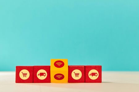 Online shopping and delivery service. E-commerce. Wooden red cubes and yellow block with trolley,...