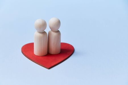 Happy family. Adopt kid. Relationship between mum and dad. Wooden figures on red heart. Copy space. Isolated on blueの写真素材