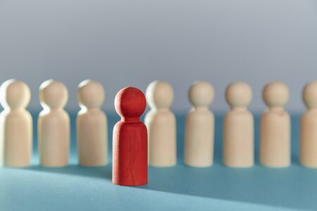 Wooden blank figures in line and one red ahead. Stand out from crowd. Think outside box. Not like everyone. Copy spaceの写真素材