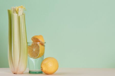 Glass with healthy lemon water. Fresh celery. Diet. Eco-friendly food concept. Green background. Copy space for text.の写真素材