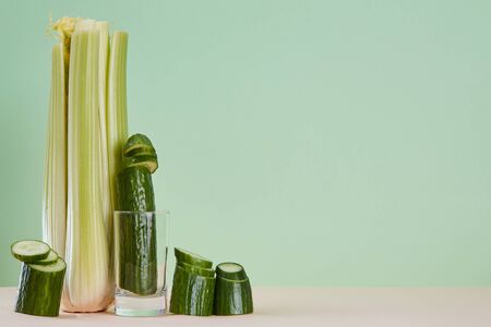 Tasty celery and cucumber isolated on green background. Healthy lifestyle. Eco-friendly food. Copy...